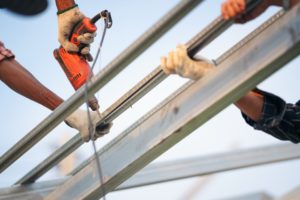 metal roofing uk man worker uses a power drill to attach a cap metal roof