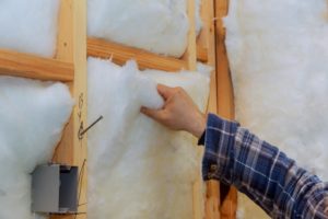 worker in insulating rock wool insulation in wooden frame for future house wall for comfortable warm